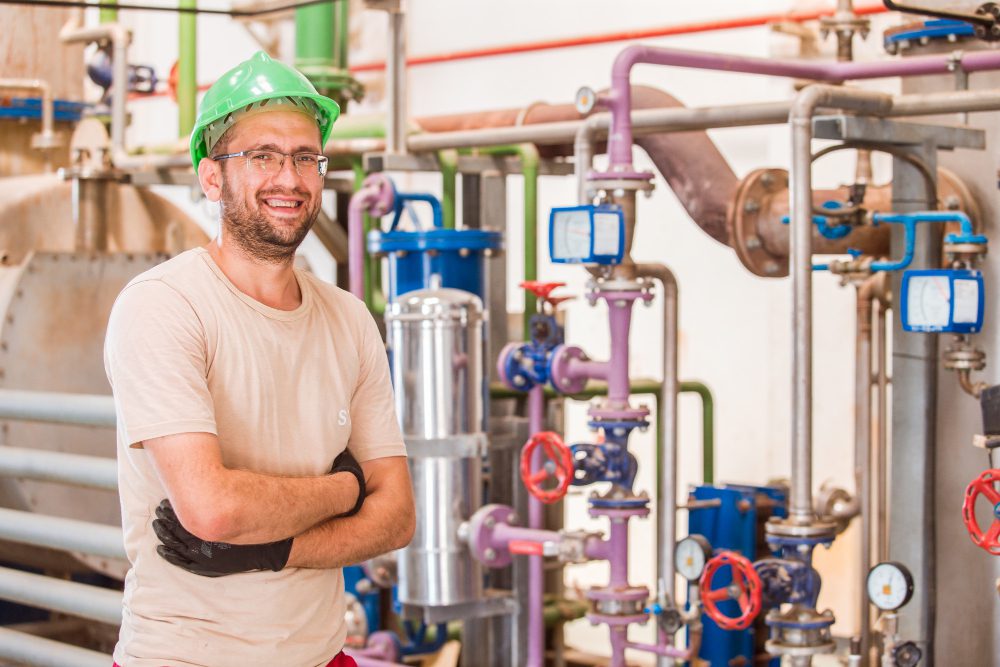 happy-industry-worker-posing-smiling-inside-factory-with-bars-pipes-around happy industry worker posing smiling inside factory with bars pipes around